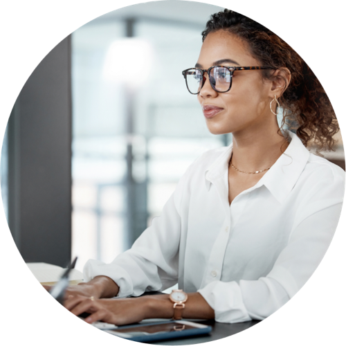Une professionnelle à lunettes travaille sur son ordinateur au bureau, illustrant la première étape pour créer son compte gratuitement en ligne sur Teledec.